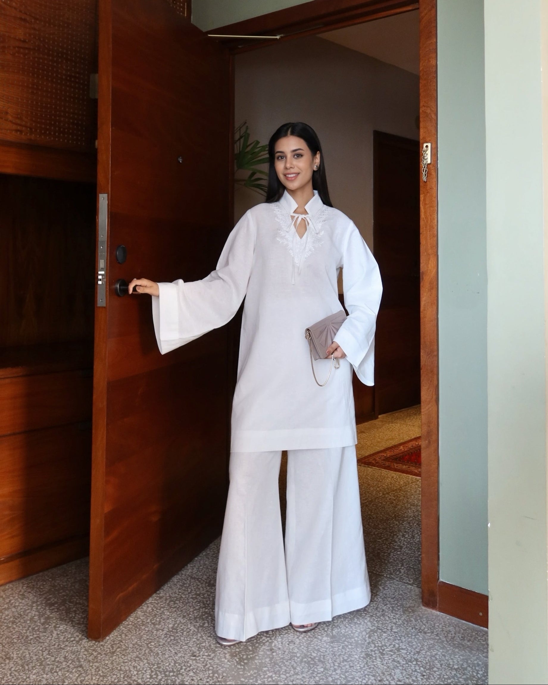 Woman in a white outfit standing in a doorway